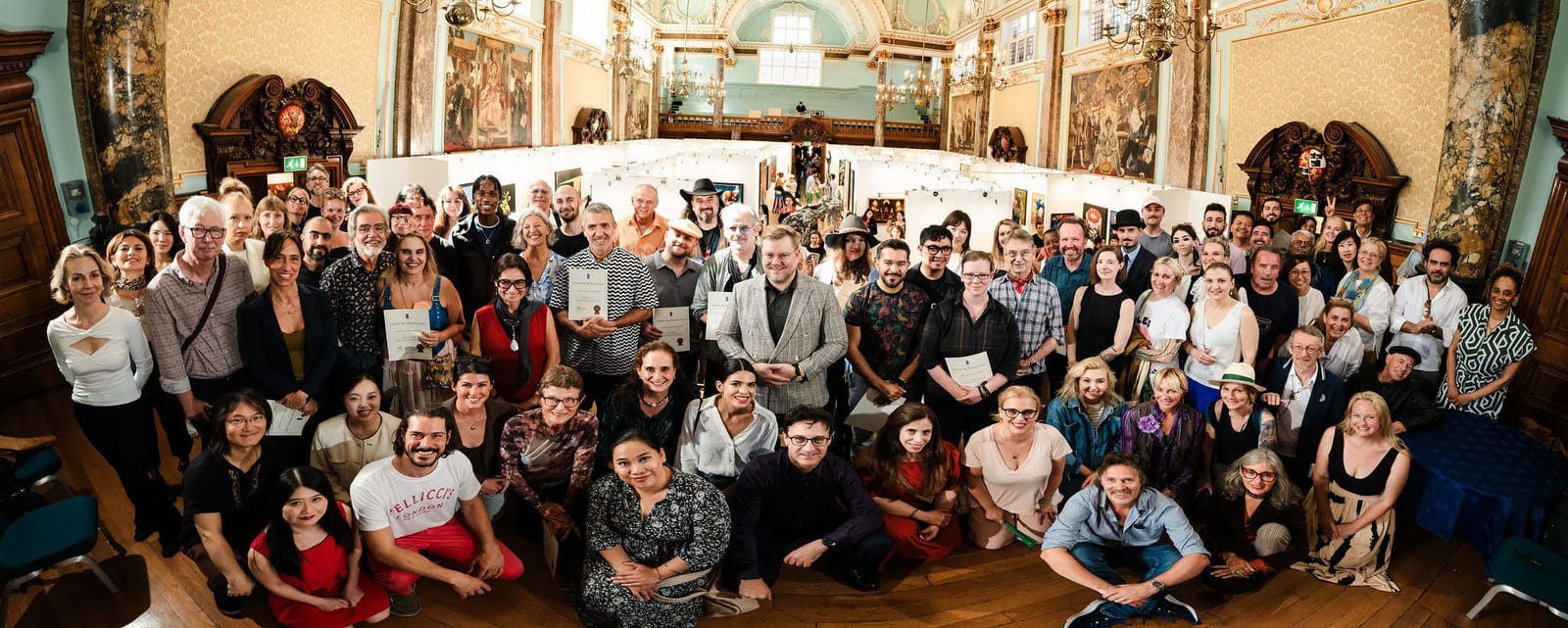 Artists gathered in the main hall for a group photograph at the awards ceremony, catalogues and certificates in hand.