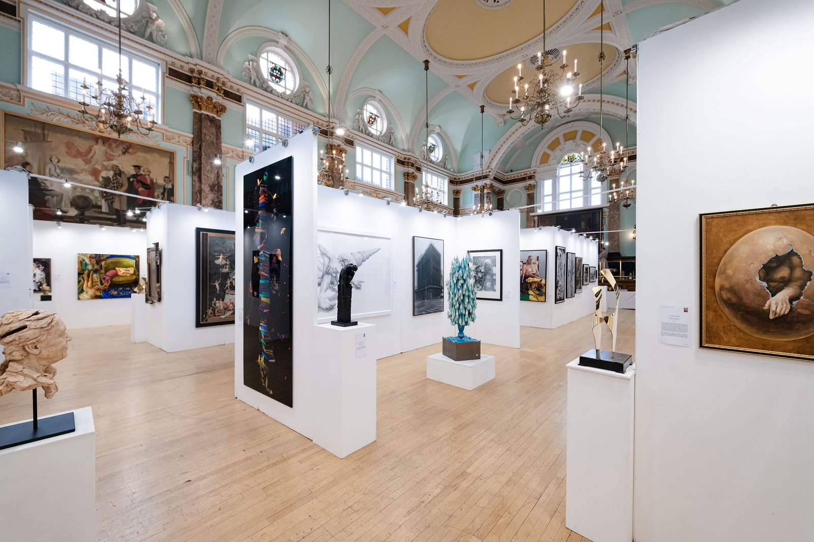 The main hall hung for the Biennale: white walls of paintings and sculpture on plinths, under the chandeliers and the painted ceiling.