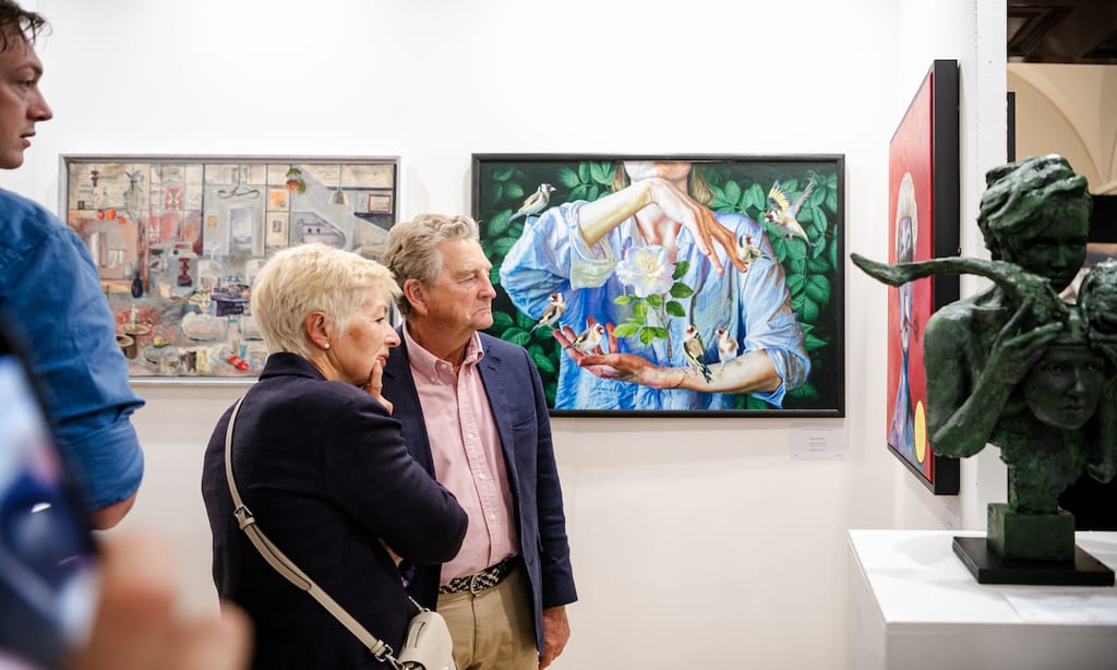 Two visitors in close conversation in front of a hung painting at the 2023 edition.