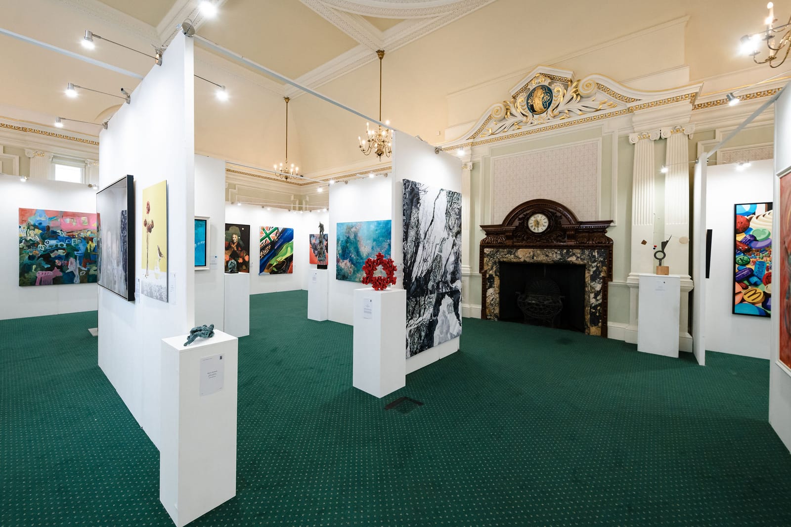 A gallery with pale green walls hung with framed works.