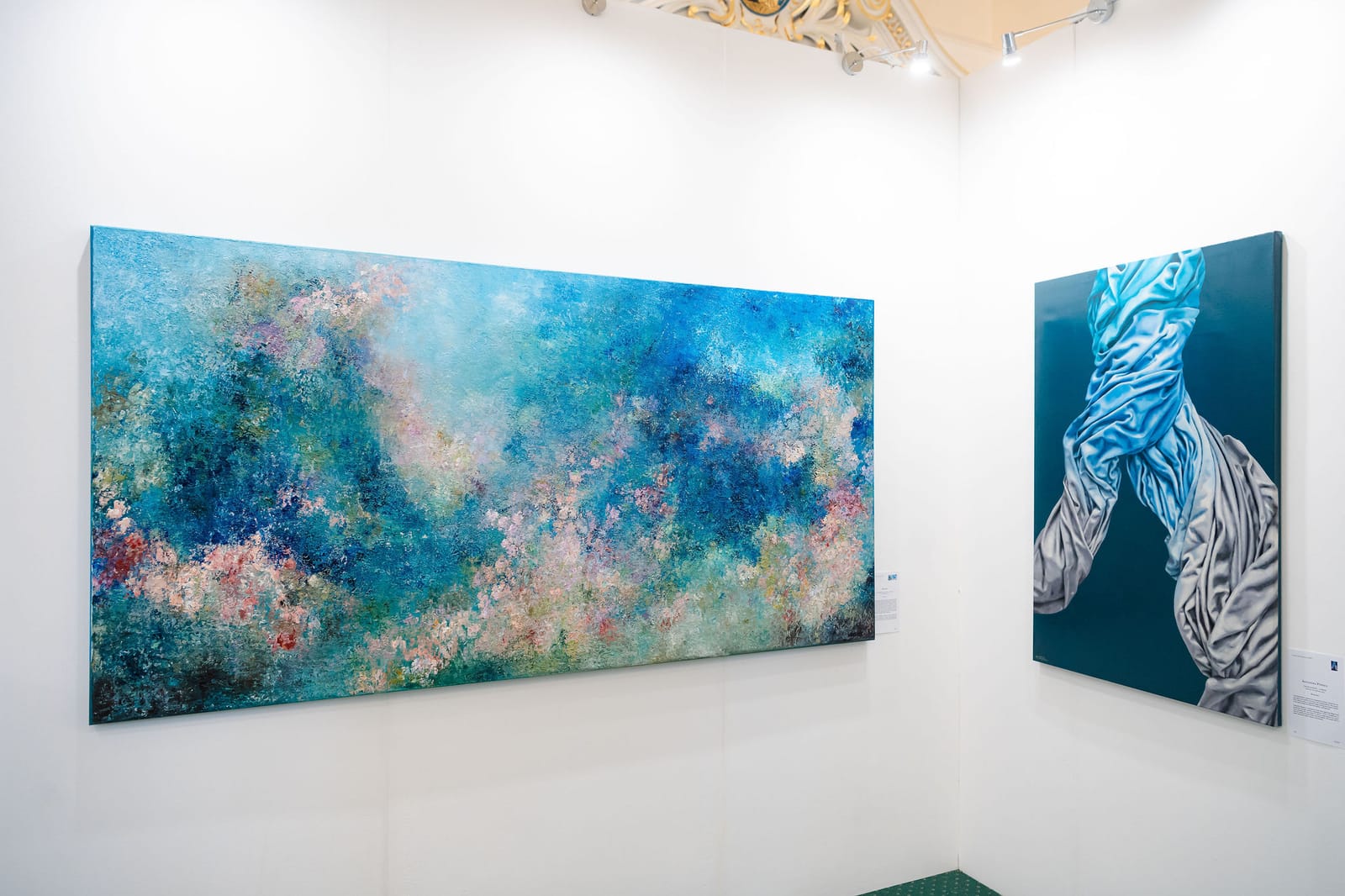 A deep blue exhibition wall hung with framed works.